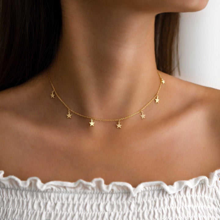 Goldene Sternen-Halskette auf weißem Hintergrund, eleganter Schmuck für Damen.