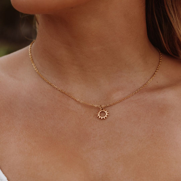 Goldene Sonnenanhänger-Halskette auf Haut, modisches Schmuckstück, Damenaccessoire.