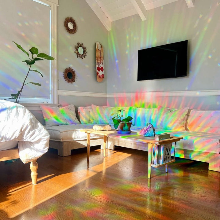 Wohnzimmer mit Regenbogen-Lichtspiel, Suncatcher-Effekt, helle Einrichtung, Pflanzen, Holzboden.