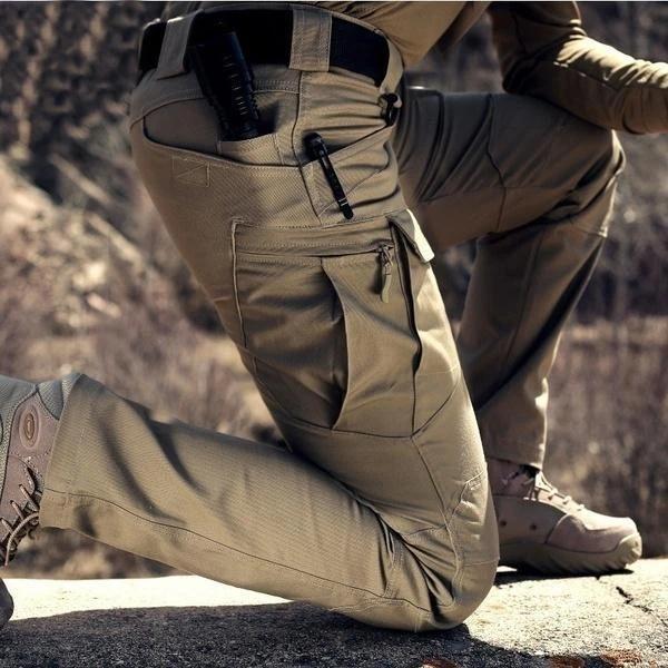 Detail klečícího muže v khaki kalhotách s velkou stehenní kapsou na zip, v exteriéru 2