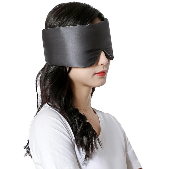 Frau trägt schwarze Seidenschlafmaske, ideal für Schlaf und Entspannung.