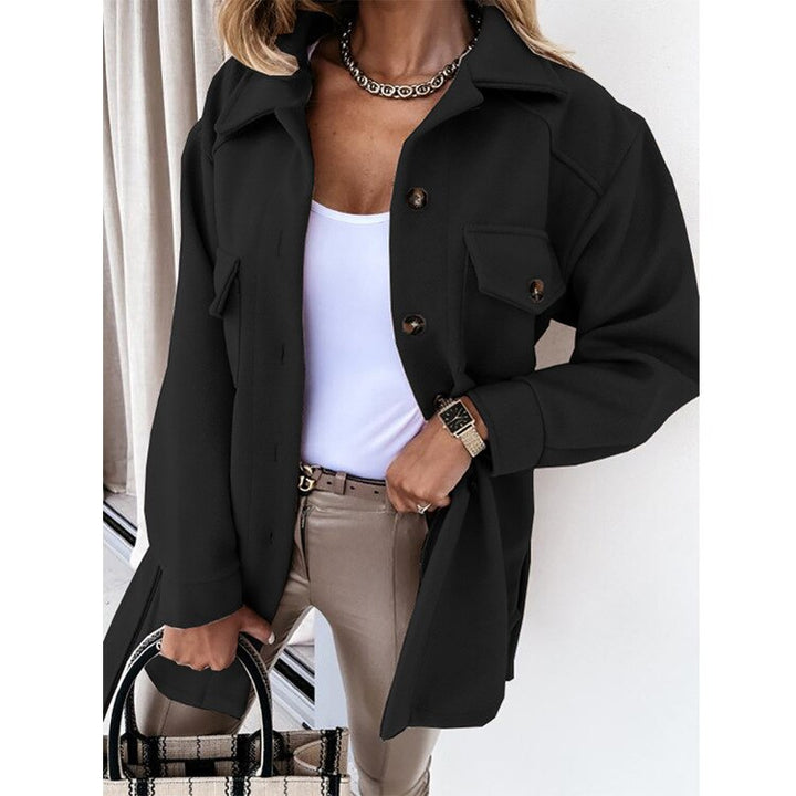 Frau in schwarzer Jacke, weißem Top, beiger Hose, mit Tasche und Uhr, modisch elegant.
