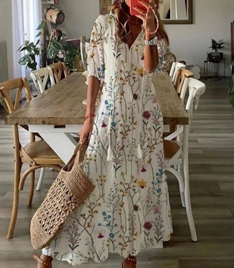 Frau in langem, geblümtem Sommerkleid mit Strohtasche in modernem Esszimmer.