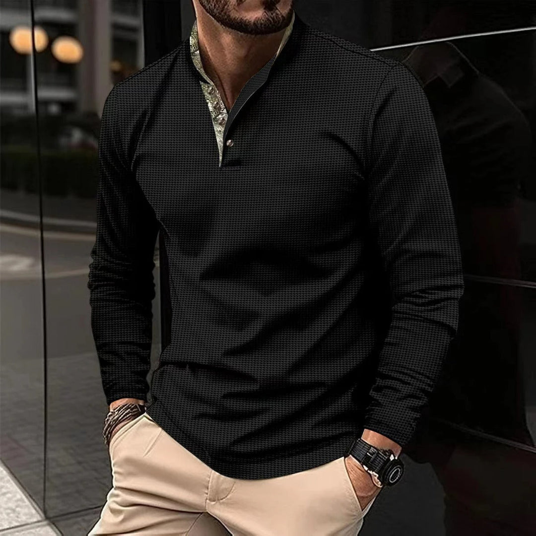 Mann trägt schwarzes Langarmhemd, Stehkragen, elegantes Design, Herrenmode, urbaner Stil.