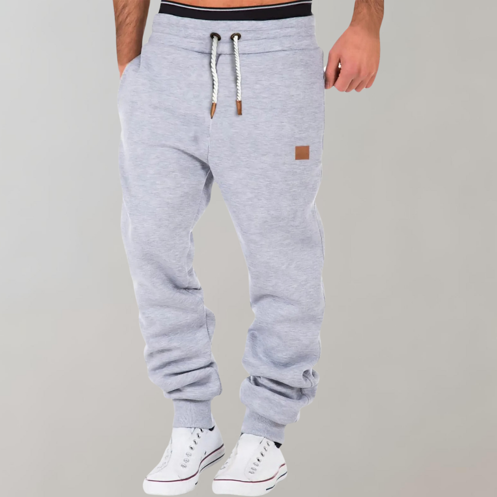 Světle šedé melírované jogger kalhoty se šňůrkou a černou gumou v pase na modelovi 4