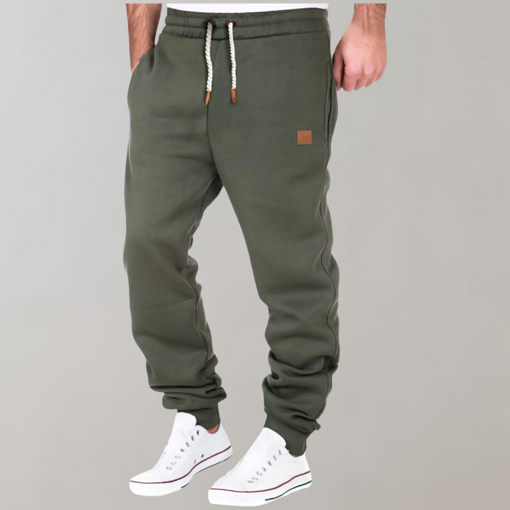Olivově zelené jogger kalhoty se stahovací šňůrkou na modelovi v bílých teniskách 3