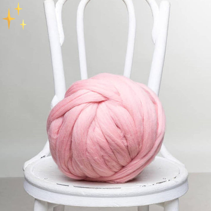 Rosa XXL-Wolle auf weißem Stuhl, ideal für Stricken und Häkeln, weiches Garn.