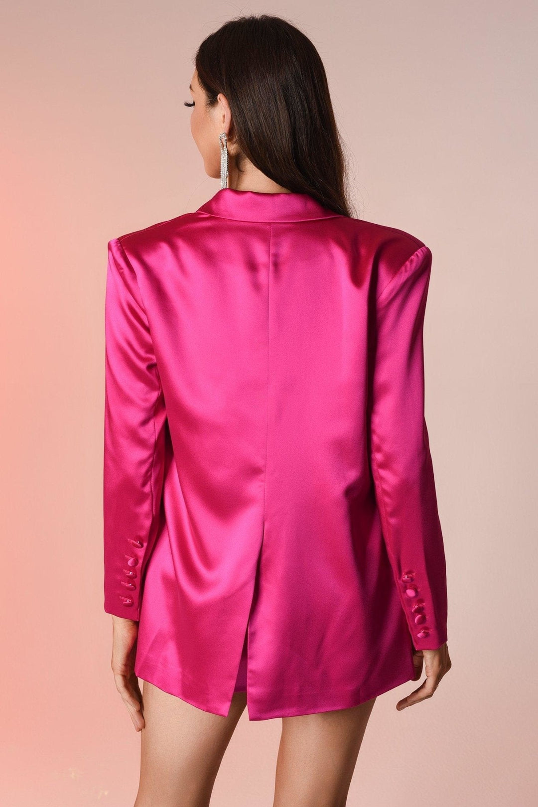 Frau in pinkem Satinblazer mit langen Ärmeln, eleganter Mode, Rückansicht.