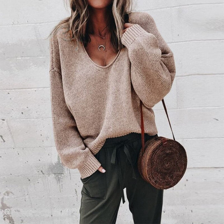 Frau in braunem V-Ausschnitt Strickpullover, lässig, mit runder Strohtasche, modisch.