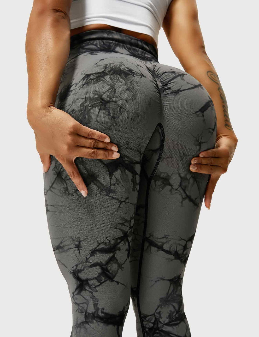 Frau in schwarz-grauen Leggings mit Marmormuster, Sportbekleidung, Fitnessmode.