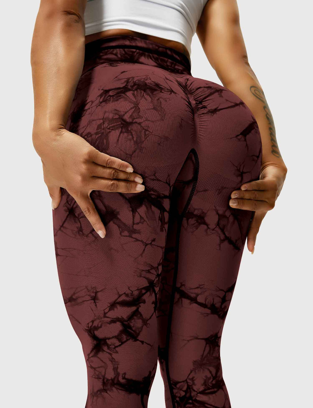 Frau in rotbraunen Leggings mit Marmormuster, Sportbekleidung, Fitnessmode, Rückansicht.