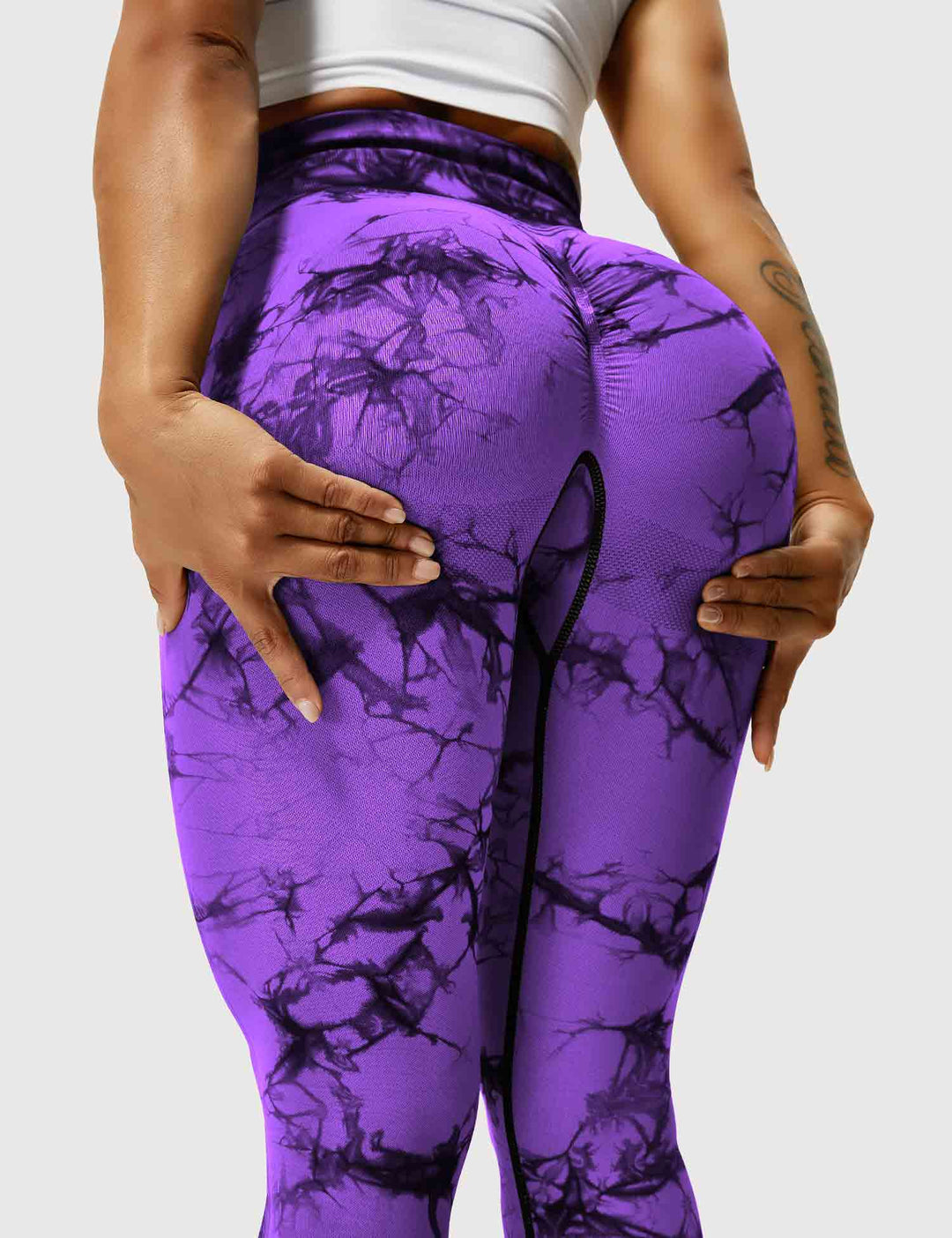Frau in lila Batik-Leggings, Sportbekleidung, Fitnessmode, elastisch, bequem, trendig.