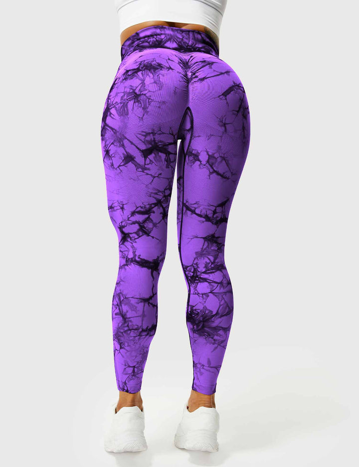 Frau in lila Marmor-Leggings, hoch tailliert, Sportbekleidung, Fitnessmode, Rückansicht.
