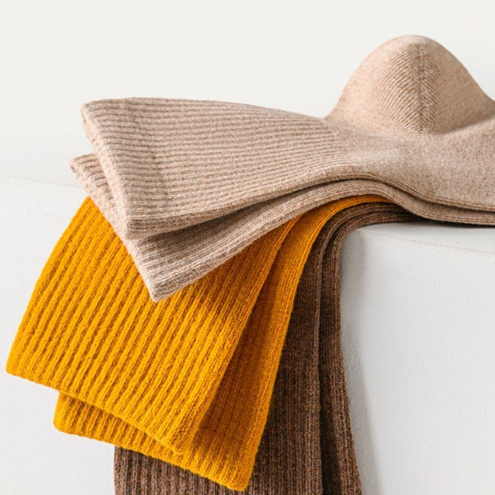 Beige, gelb und braun gestrickte Wollschals auf weißem Hintergrund.