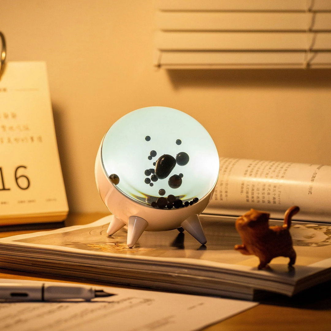 Runde LED-Tischlampe mit schwarzem Blasenmuster auf Schreibtisch, modernes Design, warmes Licht.