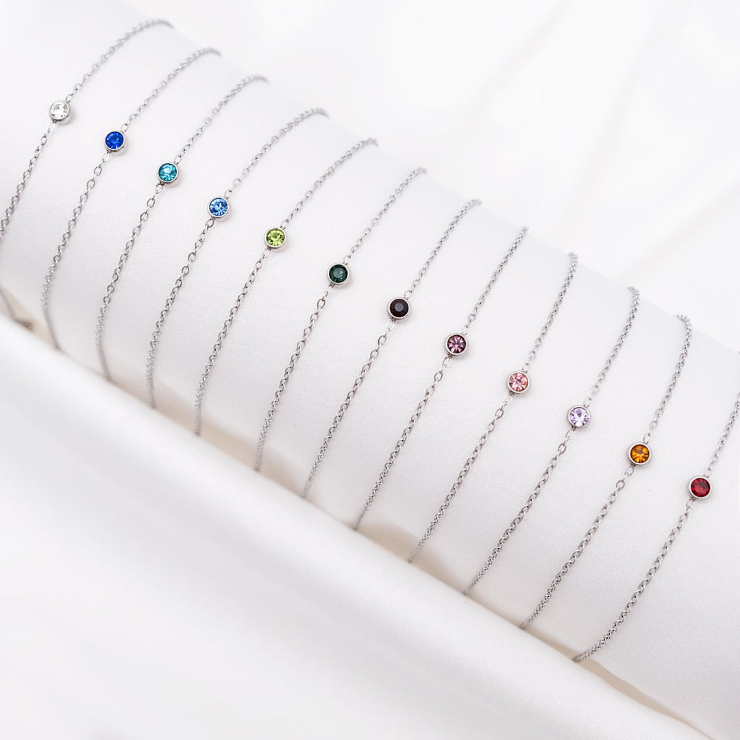Silberne Geburtsstein-Armbänder auf weißem Hintergrund, verschiedene Farben, Schmuck für Damen.