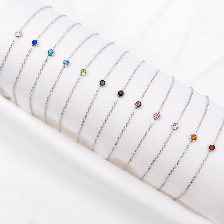 Silberne Geburtsstein-Armbänder auf weißem Hintergrund, verschiedene Farben, Schmuck für Damen.