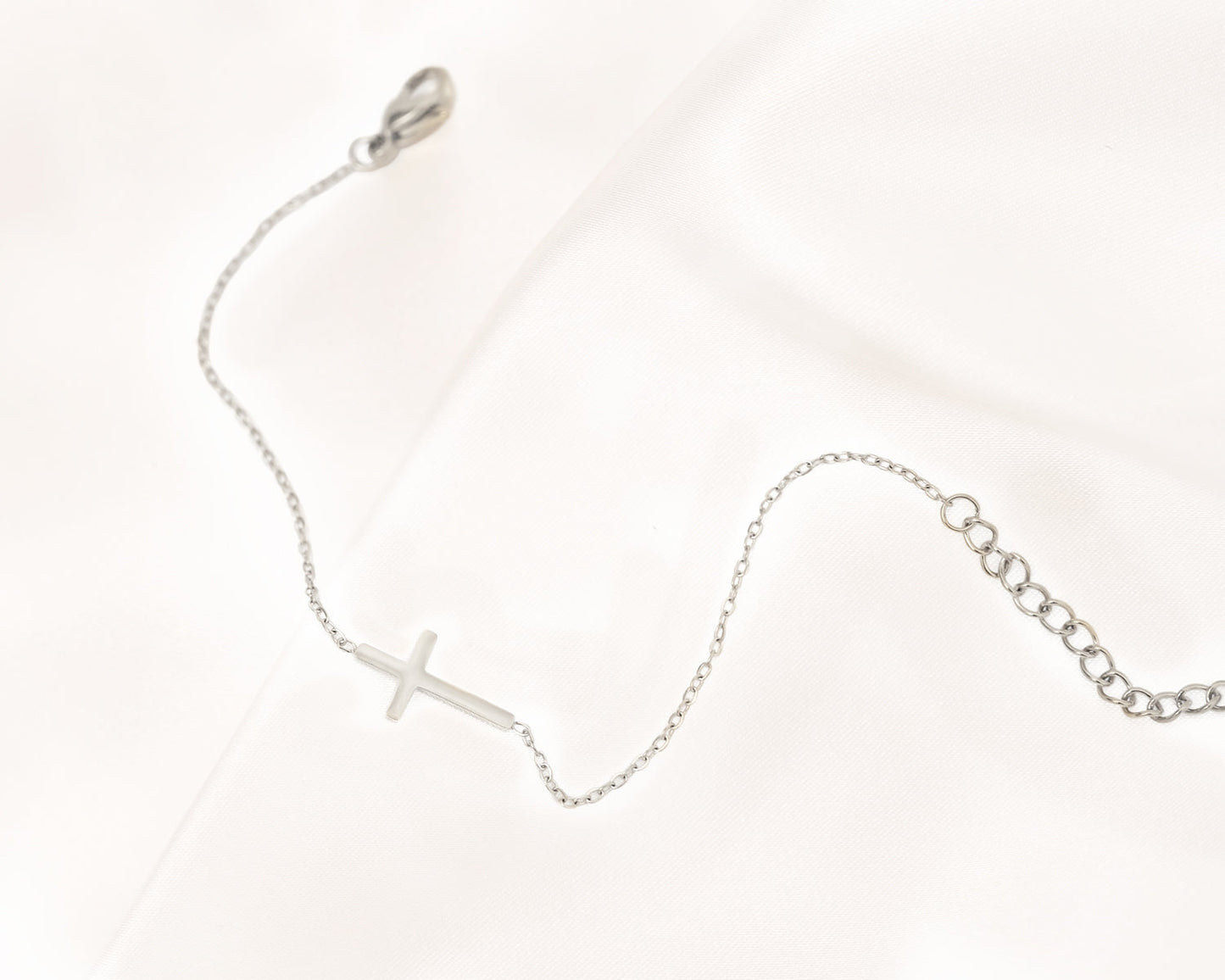 Silbernes Kreuzarmband auf Satin, filigranes Design, eleganter Schmuck, Damenarmband.