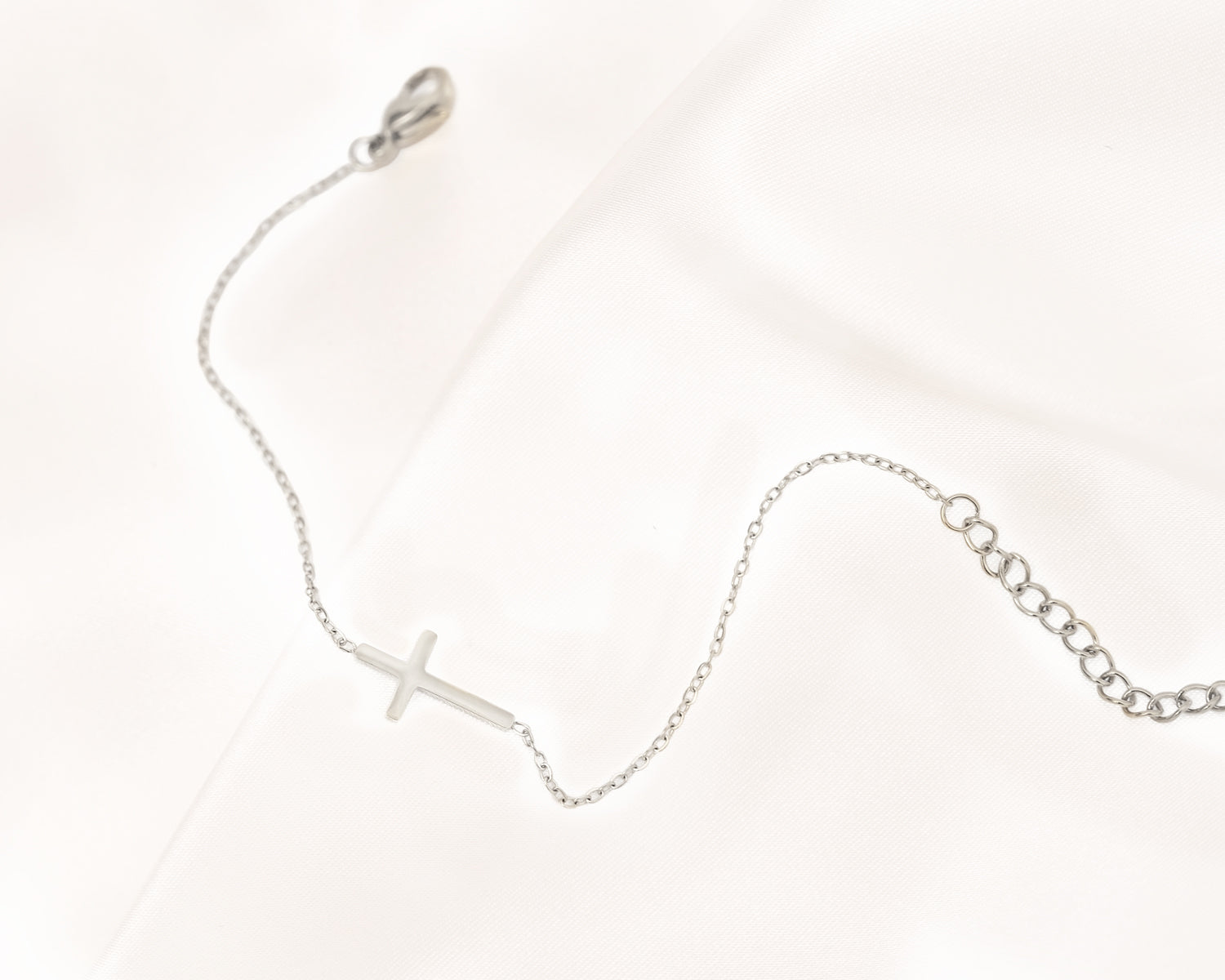 Silbernes Kreuzarmband auf Satin, filigranes Design, eleganter Schmuck, Damenarmband.