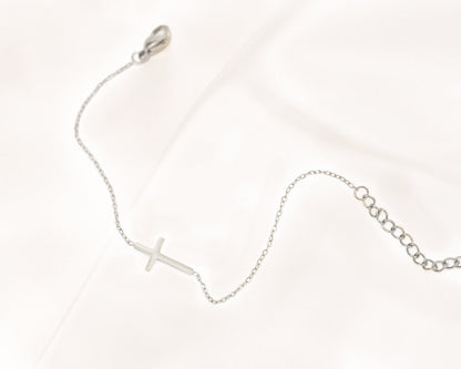 Silbernes Kreuzarmband auf Satin, filigranes Design, eleganter Schmuck, Damenarmband.