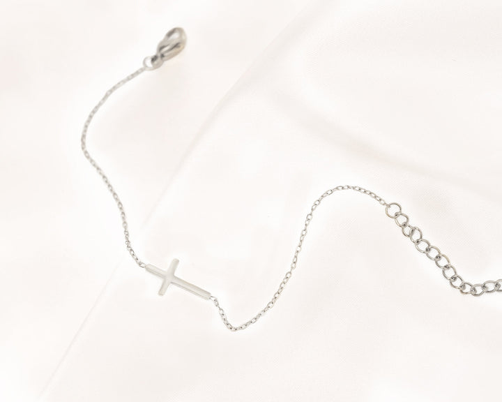 Silbernes Kreuzarmband auf Satin, filigranes Design, eleganter Schmuck, Damenarmband.
