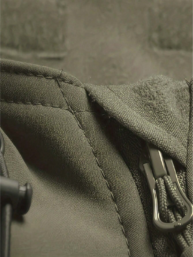 Detailní záběr na šev, zip s poutkem a látku v olivově zelené barvě. 7